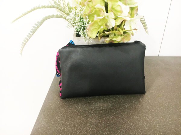 back of black clutch bag with leaves in the background